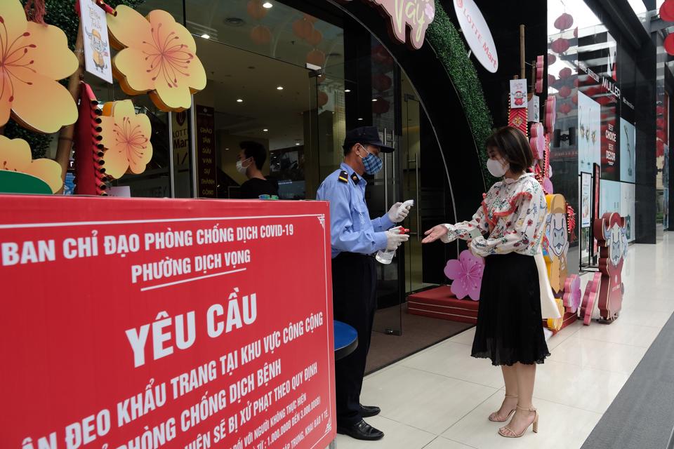 Người dân thực hiện biện pháp phòng dịch trước khi vào Trung tâm thương mại trên địa bàn Cầu Giấy, Hà Nội. Ảnh: Phạm Hùng