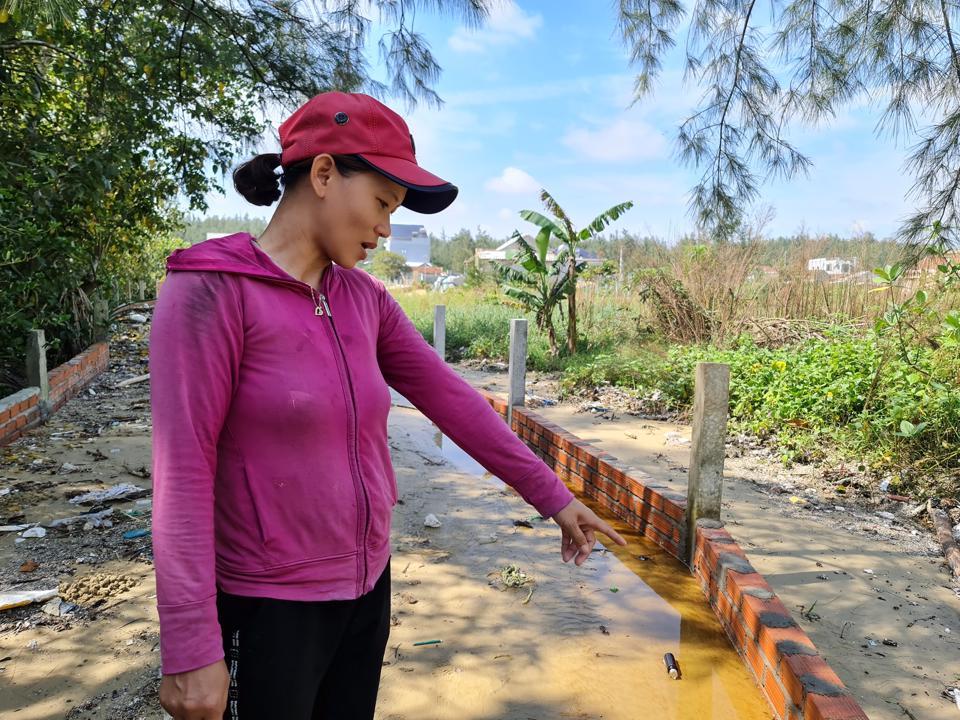 Hàng rào do gia đình bà Tình xây để chắn sóng bị cát phủ mất mấy lớp gạch.