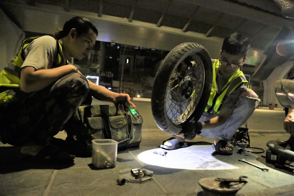 Các thành viên đội Cứu hộ Hà Nội sửa xe miễn phí trong đêm cho người đi đường. Ảnh: Phạm Công