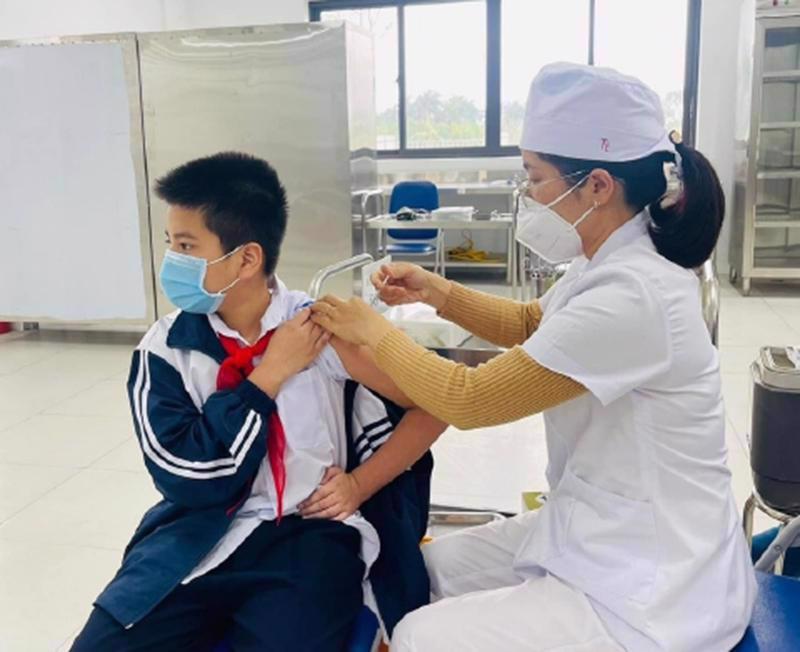 Nhân viên y tế tiêm vaccine Covid-19 cho học sinh.