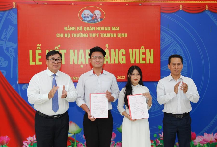 Bí thư Quận ủy, Chủ tịch HĐND quận Hoàng Mai Nguyễn Quang Hiếu (bên trái) trao Quyết định kết nạp đảng viên cho 2 học sinh lớp 12 tại trường THPT Trương Định. (Ảnh: Đông Hùng)