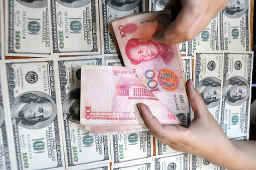 Đồng nhân dân tệ và đồng USD. Ảnh: Xinhua