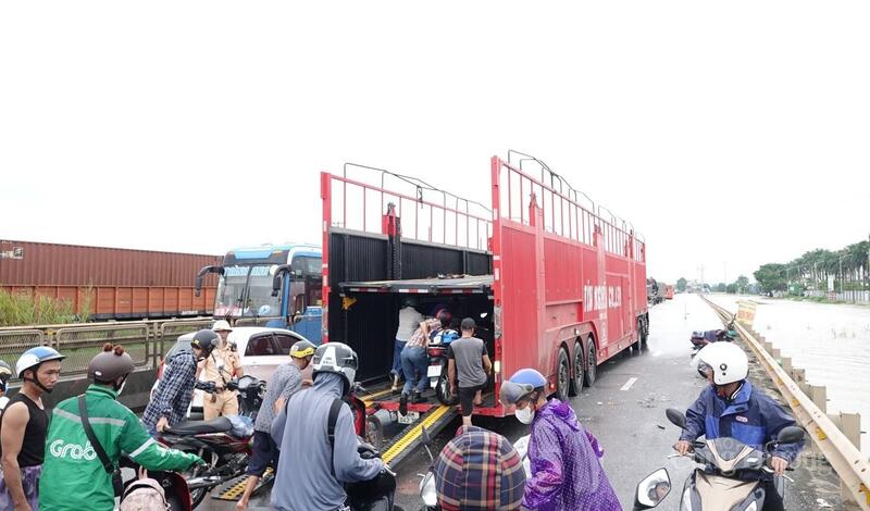 Đươc sự đồng ý của chủ xe, các xe máy được 'quá giang' xe tải vượt đoạn ngập