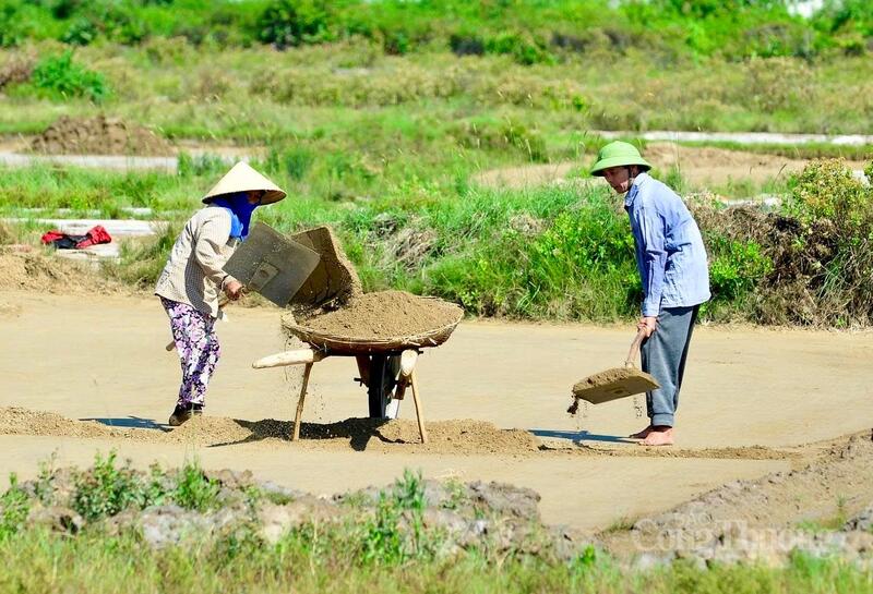 Dùng nước biển lọc qua cát đó sẽ được nước mặn hơn gọi là nước mặn độ 2. Lại tiếp tục phơi cát và dùng nước mặn độ 2 lọc qua cát đã phơi được nước mặn độ 3. Sau khi đổ đất, diêm dân sẽ múc nước từ kênh rải vào đất nền, mục đích làm cho đất nền đỡ khô, tăng độ thấm lọc cho nước muối. Ảnh: Quốc Anh